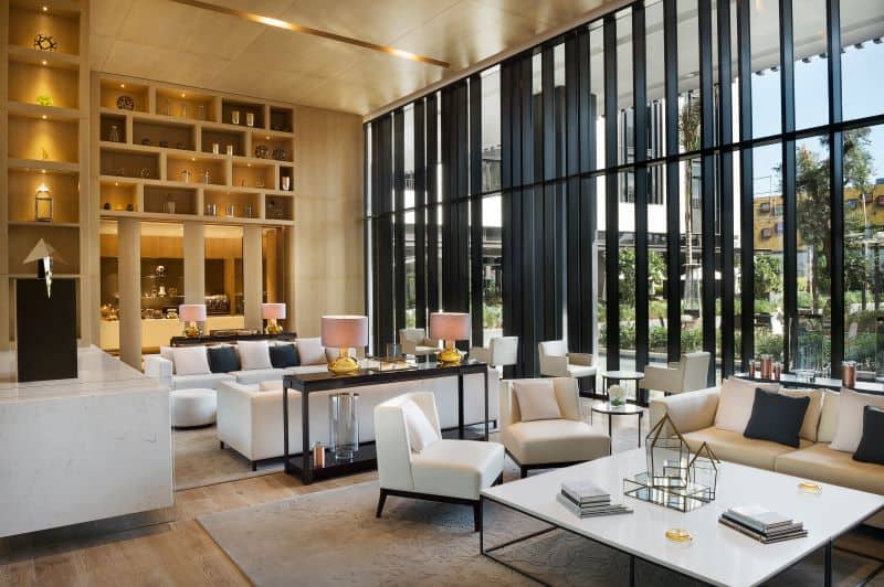 Upscale lobby area with white couches and chairs and floor-to-ceiling windows