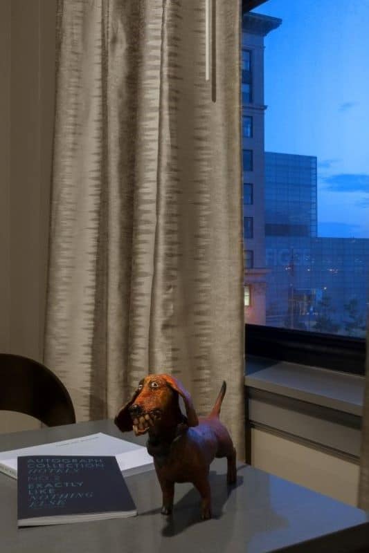 Figurine of a Dashund on a desk beside a city view window