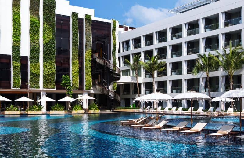 Large pool area with in-water lounge chairs and sun umbrellas surrounded by vertical gardens
