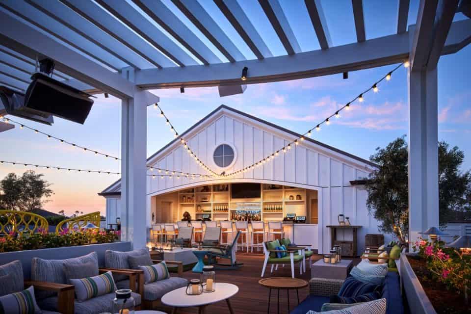 Deck area at dusk with sofa seating, bar area, string lighting