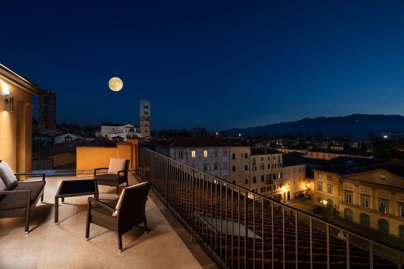Furnished outdoor terrace at night in moonlight with view of city